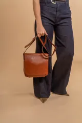 Bandolera de diseño simple con tapa frontal, confeccionada en material símil cuero. Cuenta con correa ajustable, división interna y bolsillos internos para mayor organización.