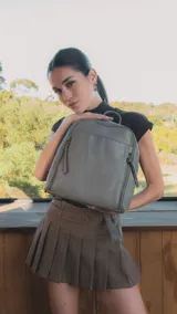 Mochila de diseño estructurado en color bordó, confeccionada en símil cuero con costuras decorativas en forma de rombos en el frente. Cuenta con un bolsillo frontal con cierre, asa superior de mano y correas regulables.