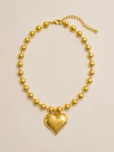 Collar dorado de cadena de esferas o cuentas metálicas, con un dije colgante en forma de corazón abombado.