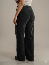 Jean de corte wide leg en color negro con efecto de desgaste. Presenta tiro medio, diseño de cinco bolsillos y cierre frontal con botón y cremallera.