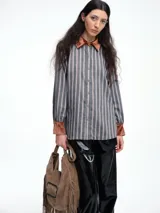 Camisa de corte relajado con estampado de rayas verticales, destacada por detalles en terciopelo en el cuello, puños y canesú. Presenta cierre frontal con botones y mangas largas.