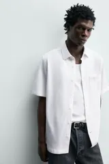 Camisa azul marino de corte regular fit confeccionada en tejido fluido de algodón y lino, con cuello solapa, manga corta, bolsillo aplicado en el pecho y cierre frontal con botones.