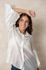 Camisa de organza blanca con cuello clásico, cierre frontal de botones y mangas tres cuartos abullonadas tipo globo con puños definidos.