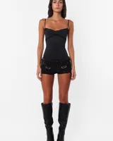 Microshort de jean negro con proceso de sobre teñido y lavado, tiro bajo y corte ajustado. Presenta costuras rojas en toda la prenda, cartera con cierre metálico, presillas largas y detalle de avío en recorte de canesú.