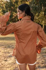 Camisa color camel con botones de madera, cuello camisero, mangas abuchonadas con puños elásticos y silueta relajada.
