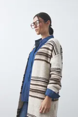 Cardigan largo de tejido de punto con diseño de rayas horizontales en tonos beige, marrón y blanco. Presenta una silueta relajada, mangas largas y frente abierto.