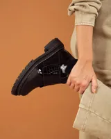 Botinetas de caña baja con suela track gruesa, combinando cuero negro en la puntera, gamuza marrón en el lateral y detalles de textura animal print tipo serpiente en tonos marrones. Presenta un cierre de solapa con velcro en el empeine.