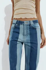 Jeans de tiro medio y pernera recta con diseño de rayas verticales en diferentes tonos de denim. Cuenta con cinco bolsillos y cierre frontal con cremallera y botón.