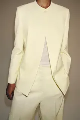 Blazer ZARA Woman Collection de corte recto, color amarillo claro, con cuello redondo, manga larga, bolsillos de ojal delanteros y cierre frontal con un botón.