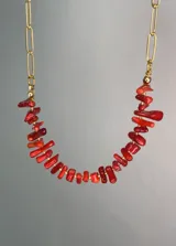 Collar con cadena de eslabones alargados dorados en la parte superior y piedras naturales de coral rojo en el centro.