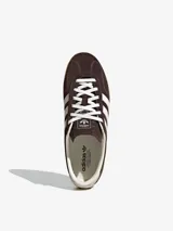 Championes Adidas Gazelle Lo Pro, modelo de corte bajo confeccionado en gamuza marrón con las tres tiras características en blanco, cordones blancos y suela de goma translúcida.
