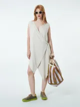 Vestido corto color beige, cruzado, sin mangas y ajustable con lazo lateral.