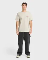 Remera Billabong de manga corta y corte regular, color beige, con gran estampado gráfico en la espalda que incluye el texto "Billabong", la ilustración de una quilla de tabla de surf y un sol estilizado.