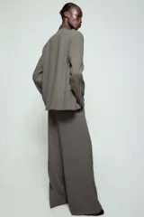 Pantalón de tiro alto con corte ancho y pernera recta. Presenta raya planchada en el delantero, bolsillos laterales y cierre frontal con cremallera y ganchos metálicos. Incluye un cinturón fino en tejido a contraste.
