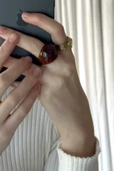 Anillo de resina en tono marrón con acabado brillante y forma redondeada.