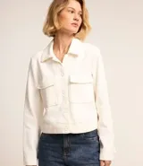 Campera corta color blanco hueso, estilo trucker, con cuello clásico, cierre abotonado, bolsillos cargo con solapa en el pecho y mangas largas con puños abotonados.