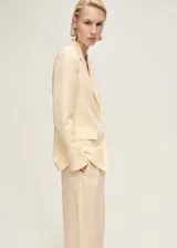 Blazer de corte recto en color amarillo pastel, confeccionado en mezcla de lino y lyocell. Presenta cuello con solapas de muesca, cierre frontal de un botón, bolsillos laterales con solapa y bolsillo de ribete en el pecho.