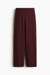 Pantalón sastrero de tiro alto, color bordó, con piernas amplias y pliegues marcados en el frente y la espalda.