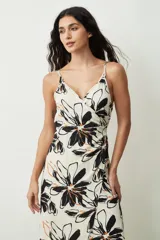 Vestido midi de tirantes finos, con escote en V y diseño cruzado estilo pareo. Presenta un estampado floral grande en tonos negros y naranjas sobre base off-white.