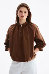 Campera bomber oversized color marrón con cuello elevado fruncido, cierre frontal y mangas raglán con puños elásticos.