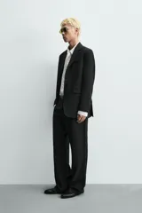 Pantalón de traje con corte relaxed fit, confeccionado en una mezcla de viscosa y lino. Presenta bolsillos laterales delanteros, bolsillos traseros de vivo y cierre frontal con cremallera y gancho oculto.