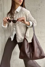 Cardigan de punto con diseño de rayas horizontales en tonos beige y blanco, cuello redondo y cierre frontal con botones. Presenta mangas largas con puños ajustados.