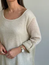 Sweater de punto color beige, de corte amplio y holgado, con escote redondo y mangas largas con presillas para arremangar.