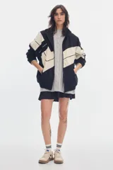 Campera oversize de denim en color negro y crudo, con diseño geométrico en bloques, cuello alto, cierre frontal y bolsillos.