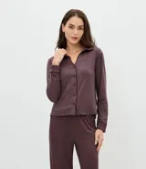 Pijama de dos piezas compuesto por una camisa de manga larga con cuello clásico, cierre frontal de botones y detalle de ribete, y un pantalón largo de corte recto. Ambas prendas presentan un diseño de rayas verticales finas en tono oscuro.