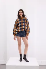 Sweater de tejido de punto con diseño geométrico a cuadros en tonos beige, terracota, bordó y celeste, de corte holgado, manga larga y cuello redondo.