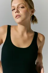 Mono corto negro de tejido de punto sin costuras, con espalda descubierta y tiras cruzadas. Estampa con logo en la espalda.