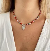 Collar corto con cuentas de colores rojo, blanco, celeste y plateado, con dije colgante de hoja plateada.