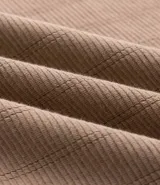 Remera manga larga beige con textura vertical en relieve y cierre frontal parcial en el cuello, confeccionada en mezcla de algodón y poliéster.