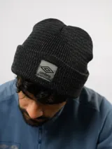 Gorro de lana gris, de punto acanalado con vuelta y parche frontal con el logo de Umbro.