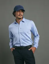 Camisa de vestir de manga larga en color azul claro, con cuello clásico, cierre frontal de botones y bolsillo en el pecho.