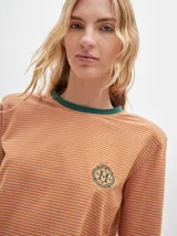 Remera de manga larga con cuello redondo y estampado a rayas horizontales en tonos marrón y negro. Tiene un logo bordado en el pecho de color rojo.