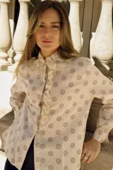 Camisa color crema con estampado de círculos marrones, cuello con volados y puntilla, y cierre frontal con botones.