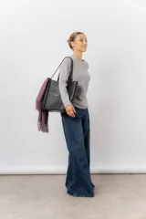 Bolso tipo tote de color marrón, confeccionado en material símil cuero texturado. Presenta un diseño estructurado con asas largas para llevar al hombro y el logo de la marca aplicado en la parte frontal.