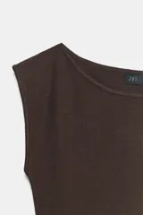 Vestido midi de punto color marrón, sin mangas, con cuello redondo y diseño ajustado que presenta el bajo con acabado plisado.