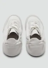 Sneaker Sofi de estilo minimalista en color gris claro, confeccionada en una combinación de piel vacuna y poliéster con detalles de gamuza en la puntera y el talón. Presenta cierre con cordones y un diseño fruncido en la parte trasera con elástico.