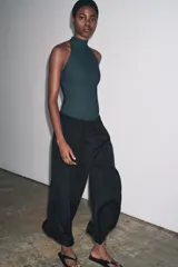 Top negro de cuello halter con cierre de botones en la parte trasera del cuello y espalda descubierta.