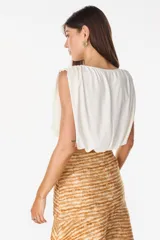 Top cropped satinado de color blanco, sin mangas, con hombros marcados y drapeado frontal.