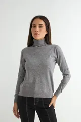 Polera de cuello alto y manga larga, confeccionada en tejido de punto fino de color gris melange, con ajuste al cuerpo.