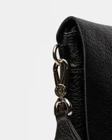 Bandolera color beige con correa ancha de tela negra con el nombre de la marca en blanco.