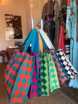 Bolso tejido con patrón de damero en varios colores, con asas de tela.