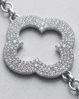Cinto de cadena metálica plateada con eslabones y dijes en forma de trébol de cuatro hojas decorados con strass brillante.