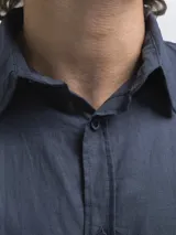 Camisa de manga larga, color blanco, con cuello camisero y botones frontales. El tejido presenta una textura visible de lino.