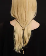 Collar con pieza metálica trenzada en acabado dorado y cordón largo regulable negro, con terminales metálicas logotipadas.