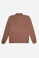 Polo de manga larga en tejido texturado color marrón, con cuello estructurado, cierre frontal de botones y detalle gráfico bordado en el pecho.