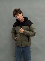 Campera puffer con capucha, diseño bicolor en verde oliva y negro, cierre frontal y bolsillos laterales.